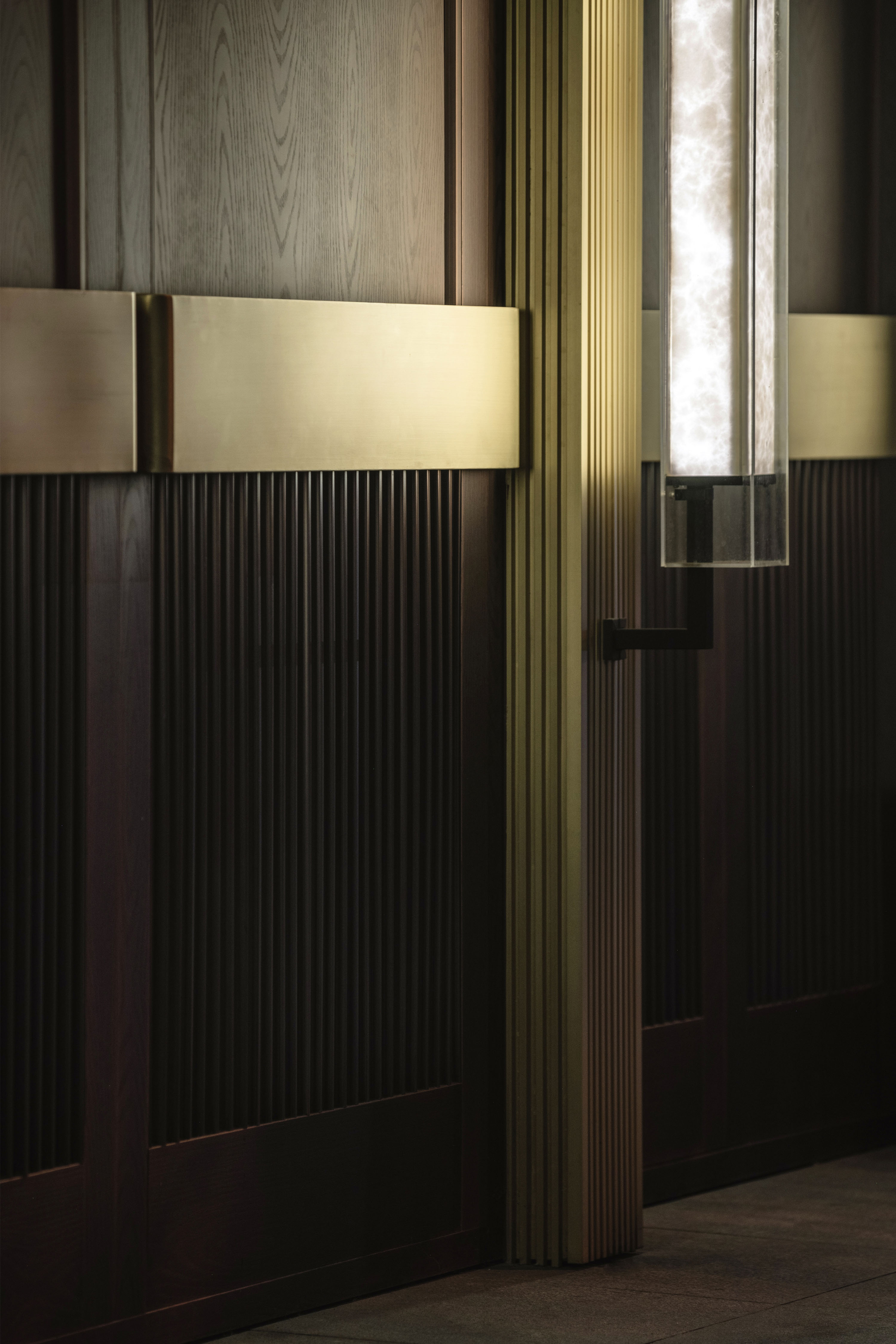 marble lights glow softly over bronze details, giving the facade a poetic presence